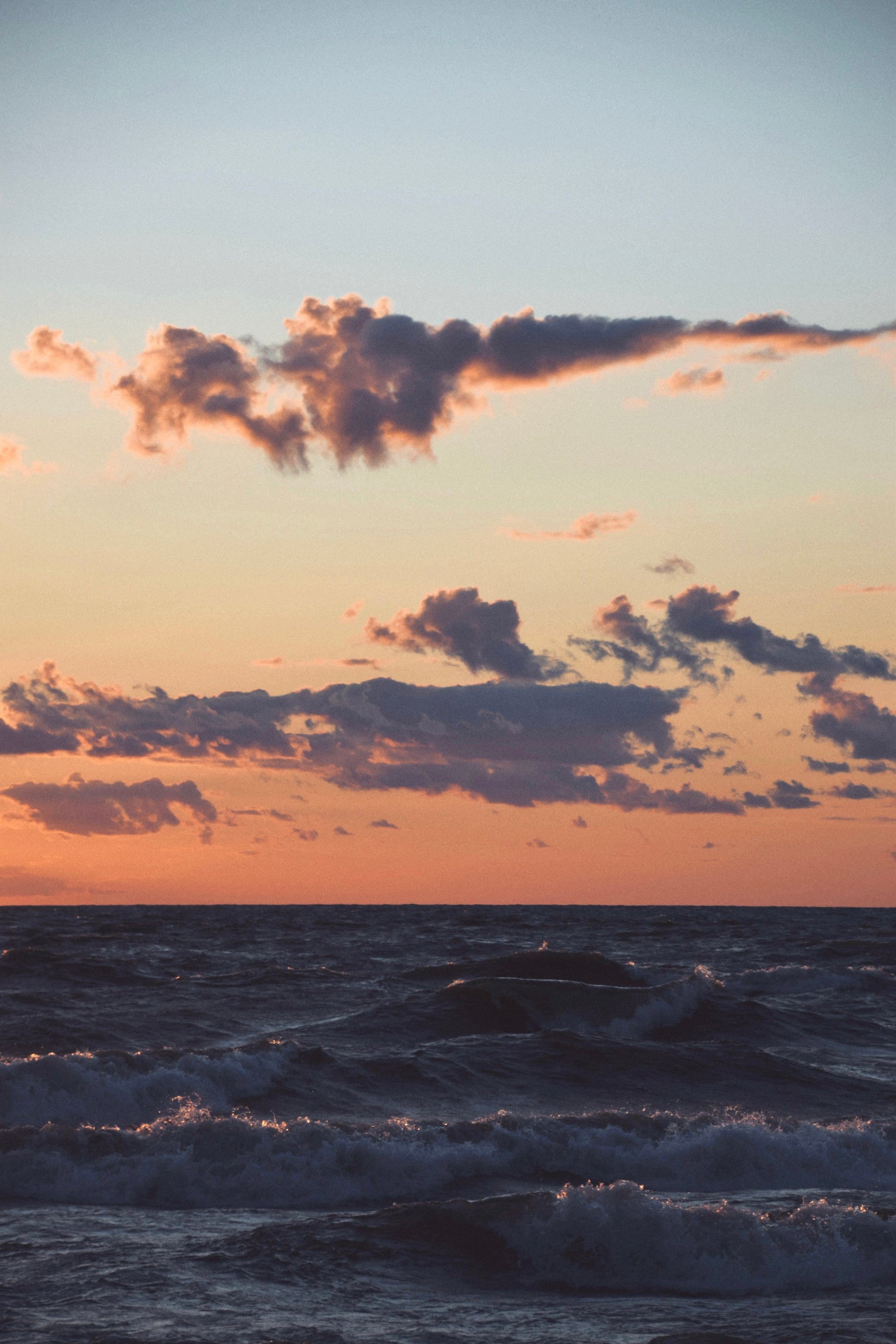 Sunset over waves on Lake Michigan, featuring colorful clouds and rippling water in serene evening light.