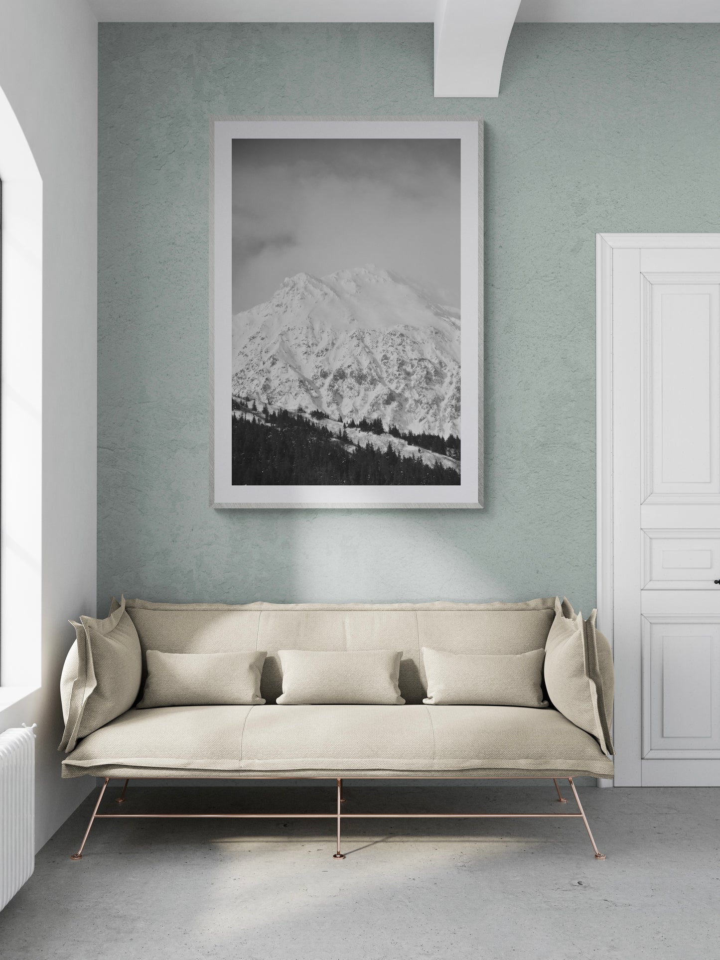 Black and white photograph of snow-capped mountains in a modern living room setting with a stylish sofa.