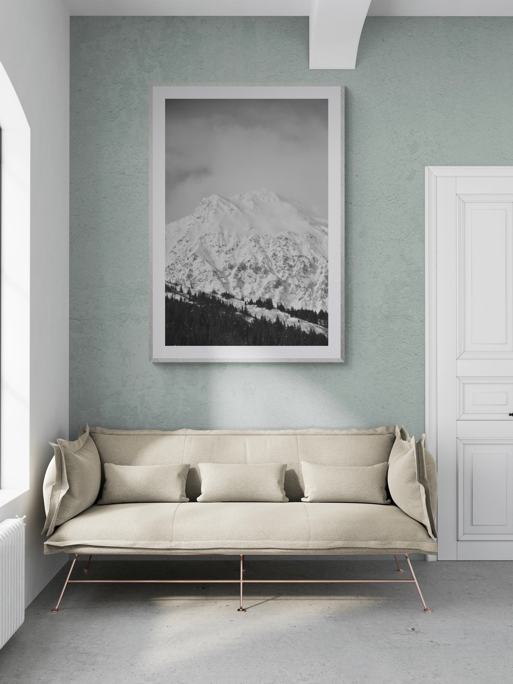 Black and white photograph of snow-capped mountains in a modern living room setting with a stylish sofa.